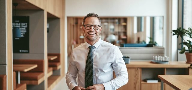 smiling-mature-businessman-standing-alone-in-an-of-2022-02-02-04-48-31-utc.jpg